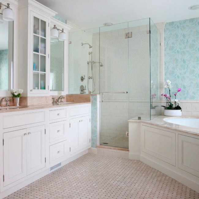cleanly remodeled bathroom with glass shower door, soaking, tub and custom shelving. The cabinets and walls are light colors.