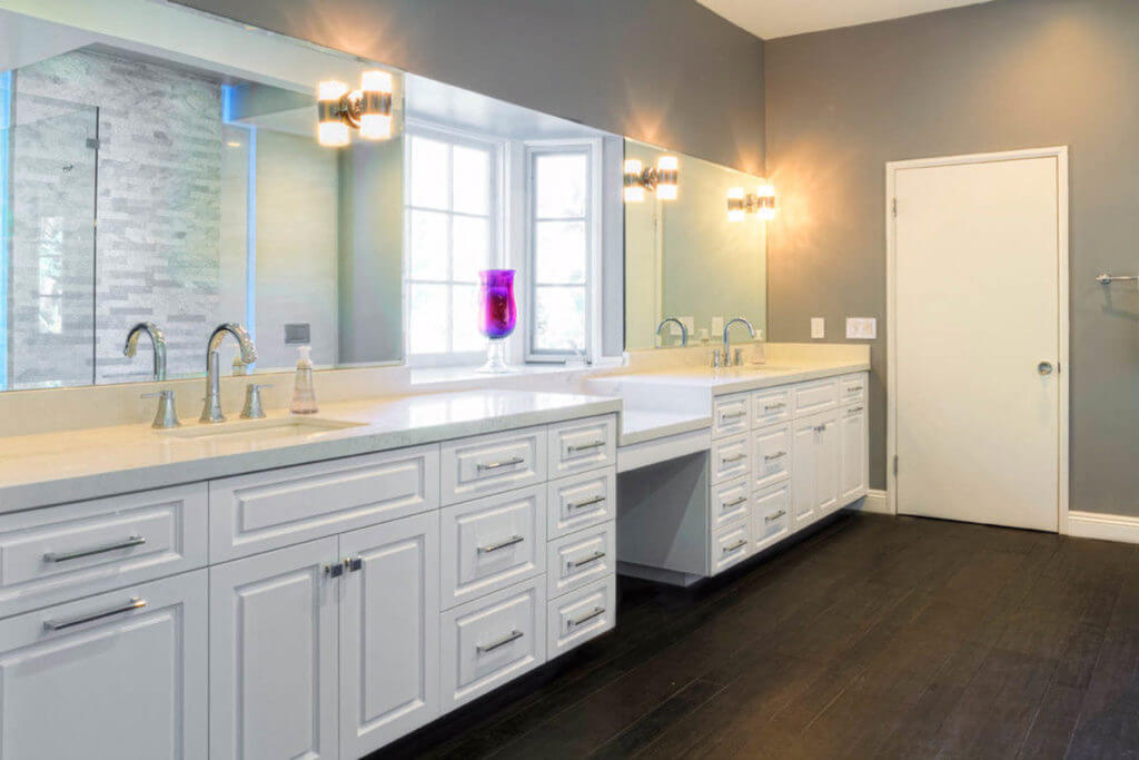 bathroom renovation with white cabinets and large mirrors