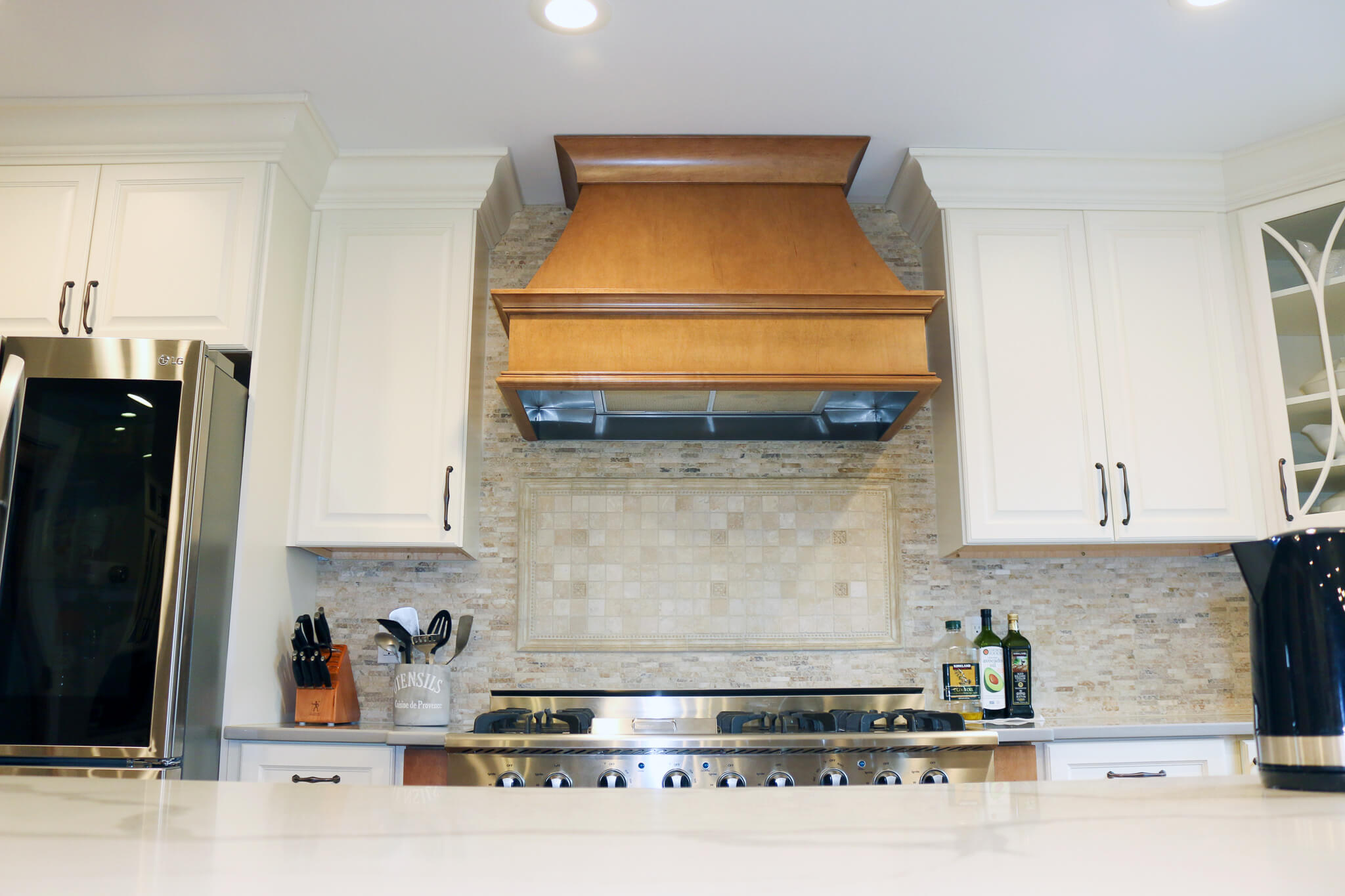 a burner with wooden hood and white cabinets on both sides