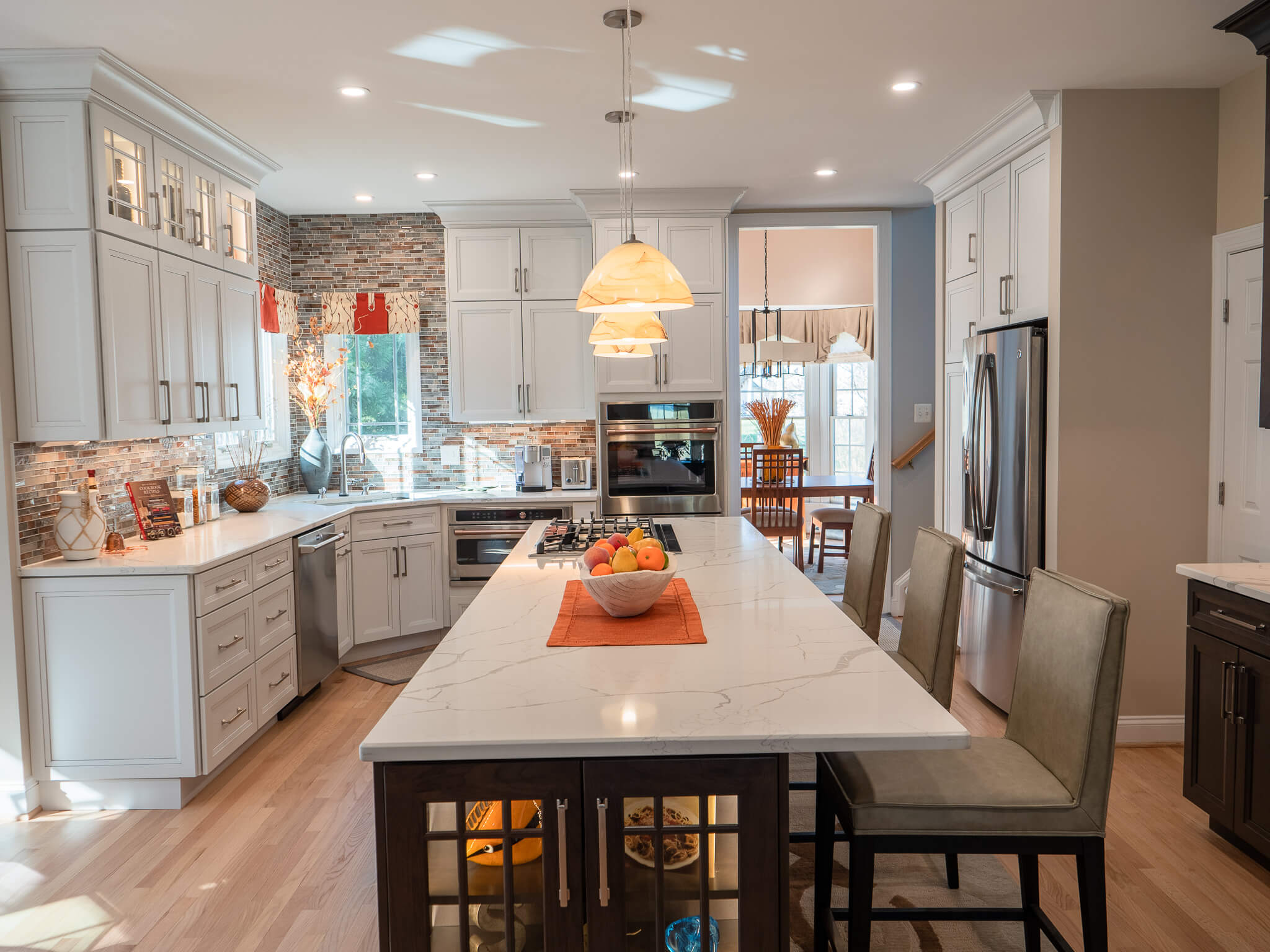 a fully renovated kitchen with white high cabinets and a centred countertop for dinning.