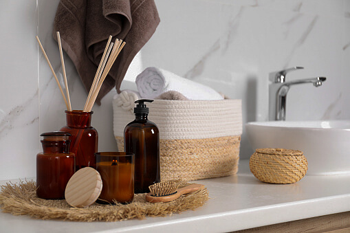 Soap dispenser, air reed freshener and burning candle on countertop in bathroom