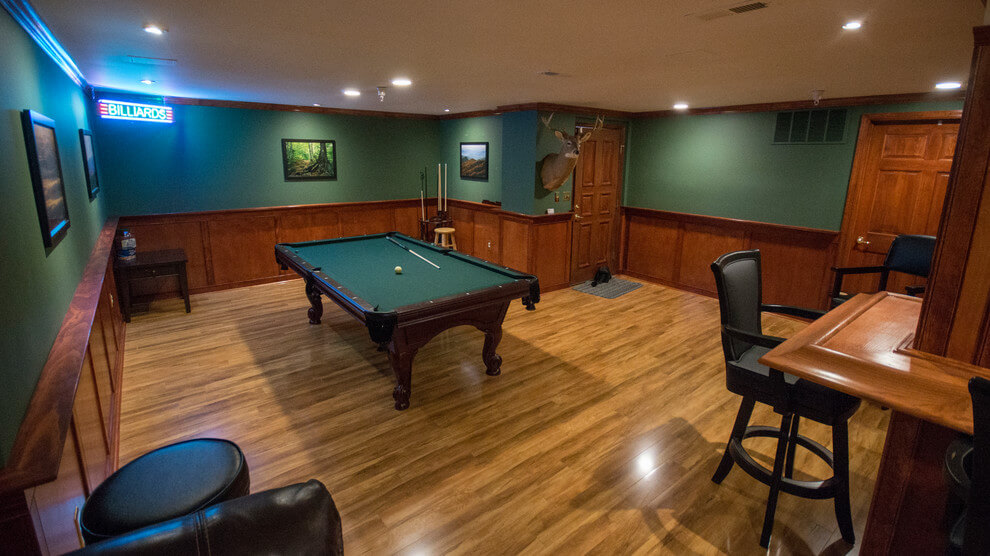 Modern basement with emerald green walls, dark wood finish, and polished wood floor