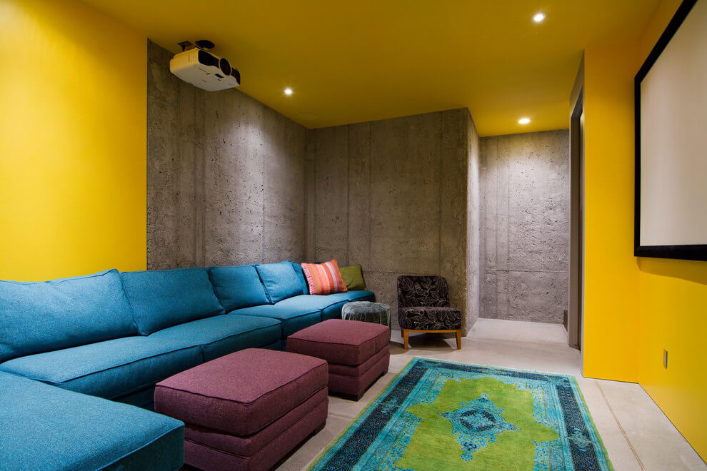 Contemporary basement with yellow walls and teal sofa