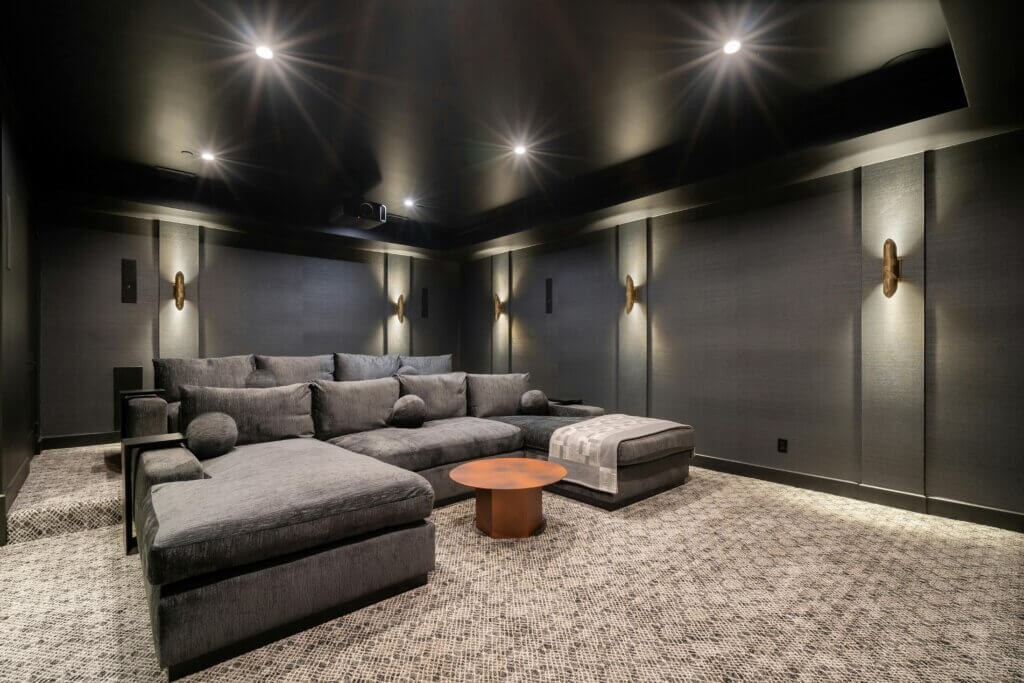 Modern charcoal grey basement with home theater and warm lighting